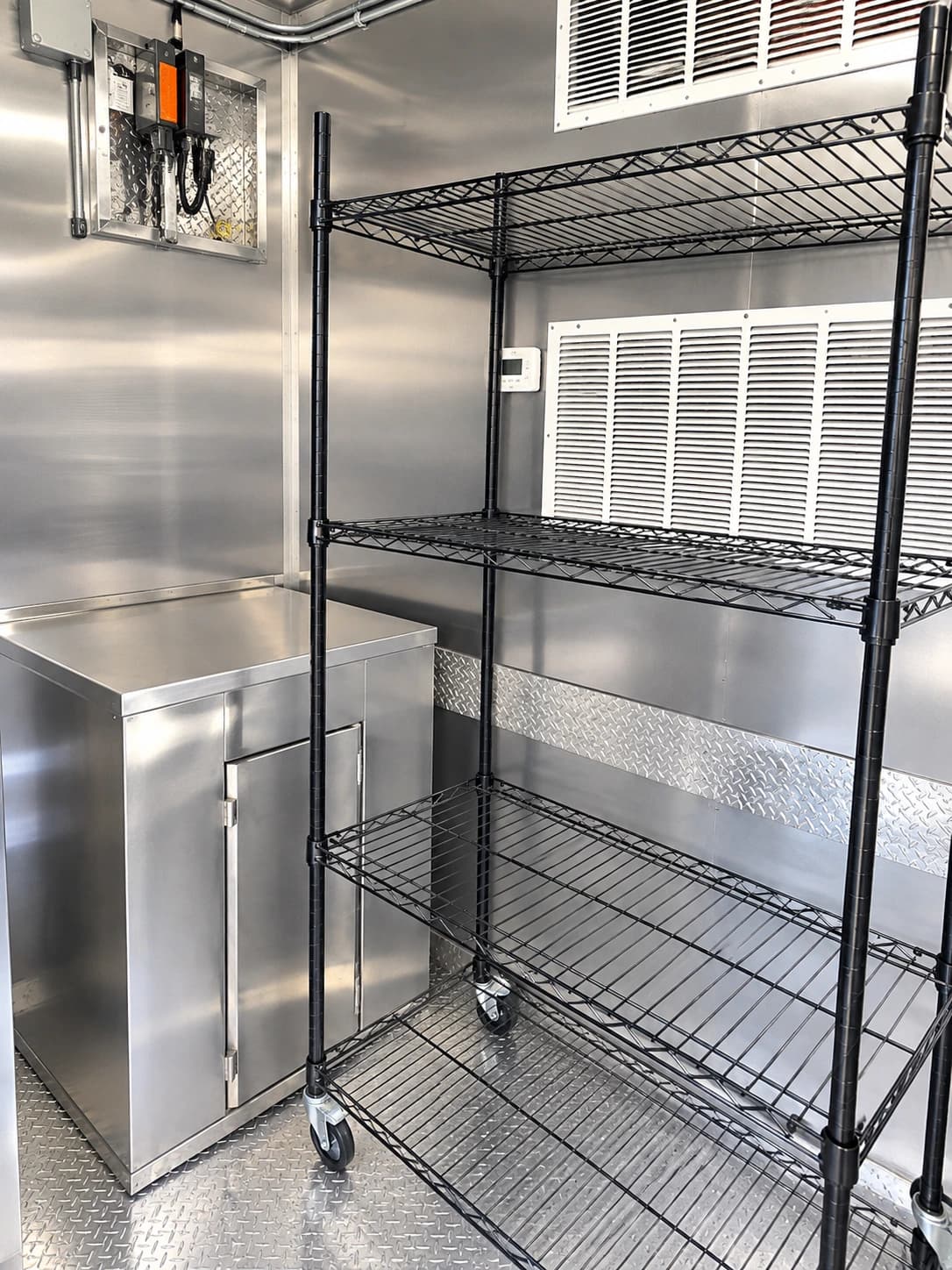 Reference mobile kitchen interior with stainless prep surfaces and storage racks